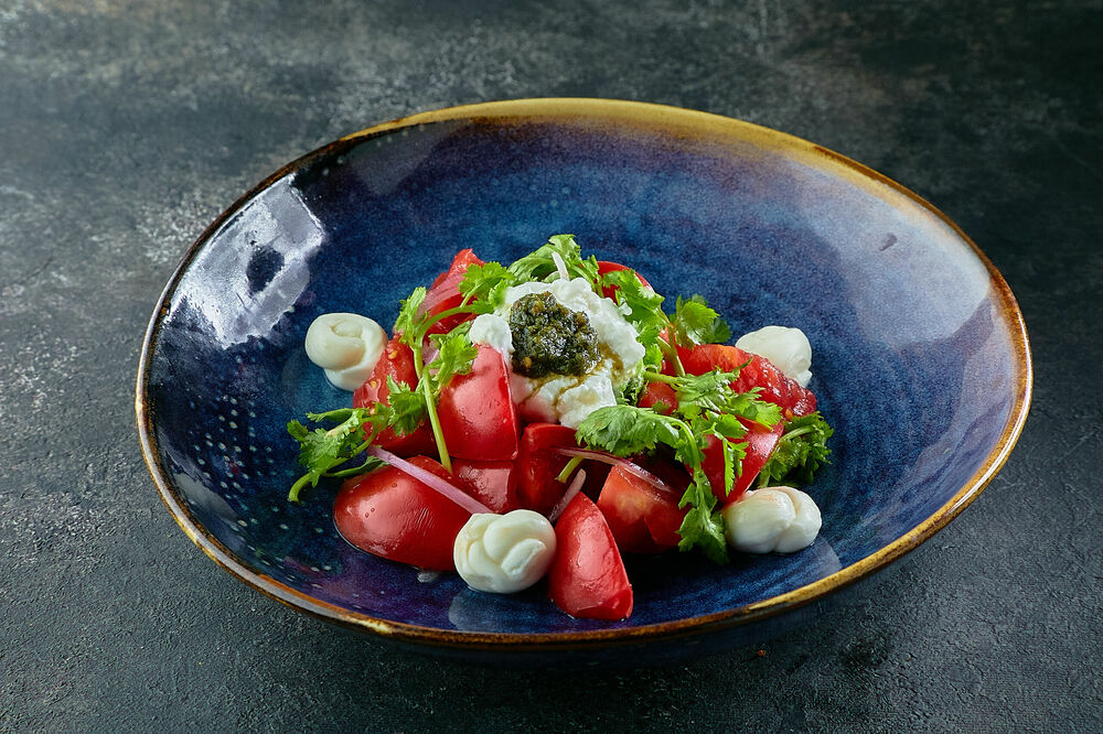 Pink tomato salad with yogurt and adjika sauce