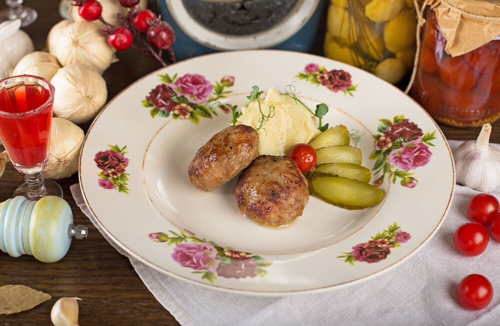 Veal and pork homemade cutlets with mashed potatoes and pickled cucumber
