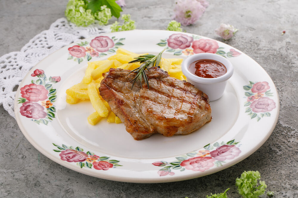 Grilled pork loin on a rib with French fries