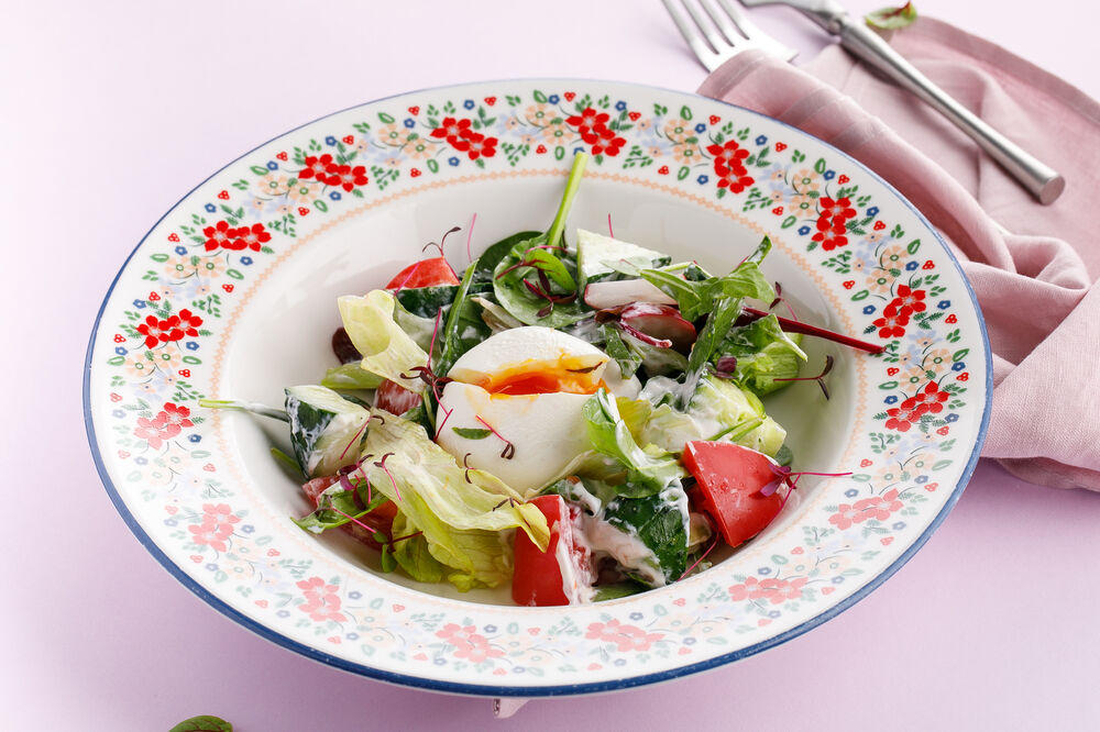 Fresh vegetable salad with sour cream and poached egg