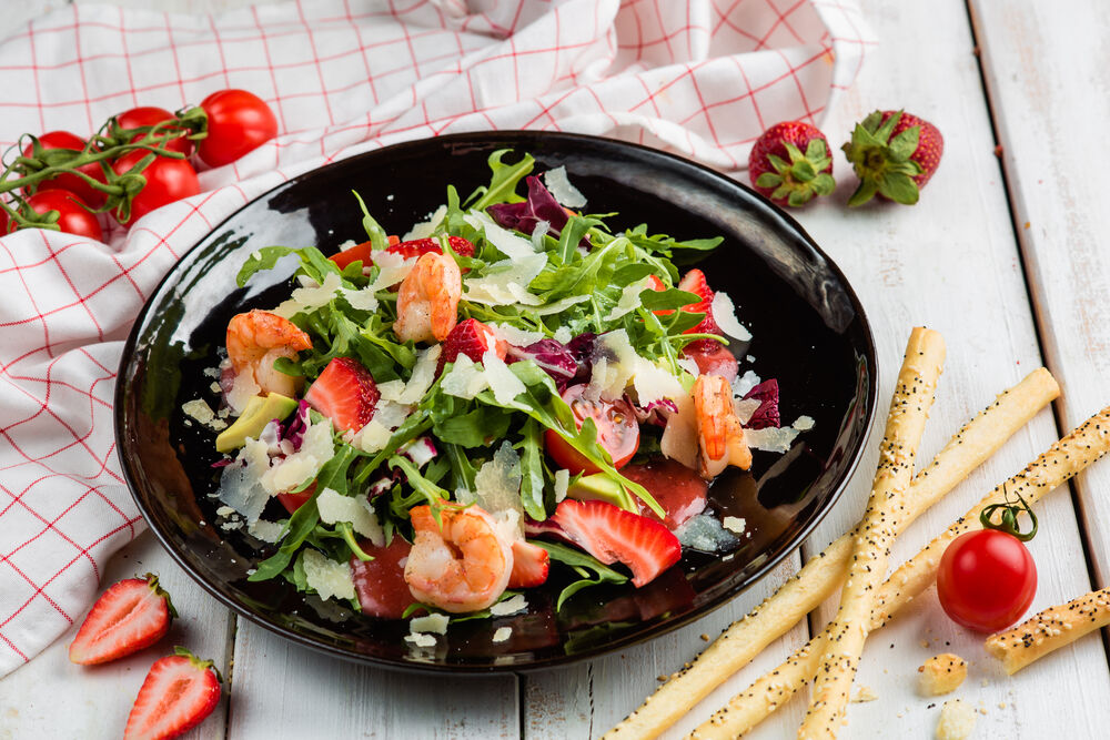 Leaves arugula with shrimp, cherry tomatoes and fresh strawberries