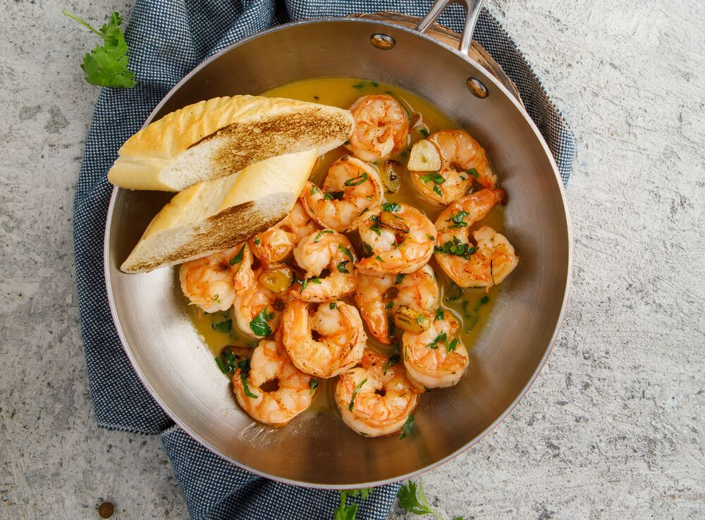 Shrimps with garlic and greens on a frying pan