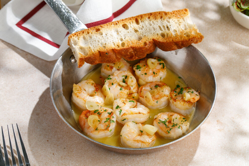 Shrimps with garlic and greens on a frying pan