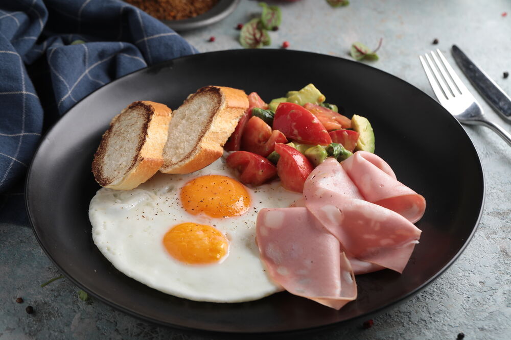 Fried eggs with mortadella and guacamole salad