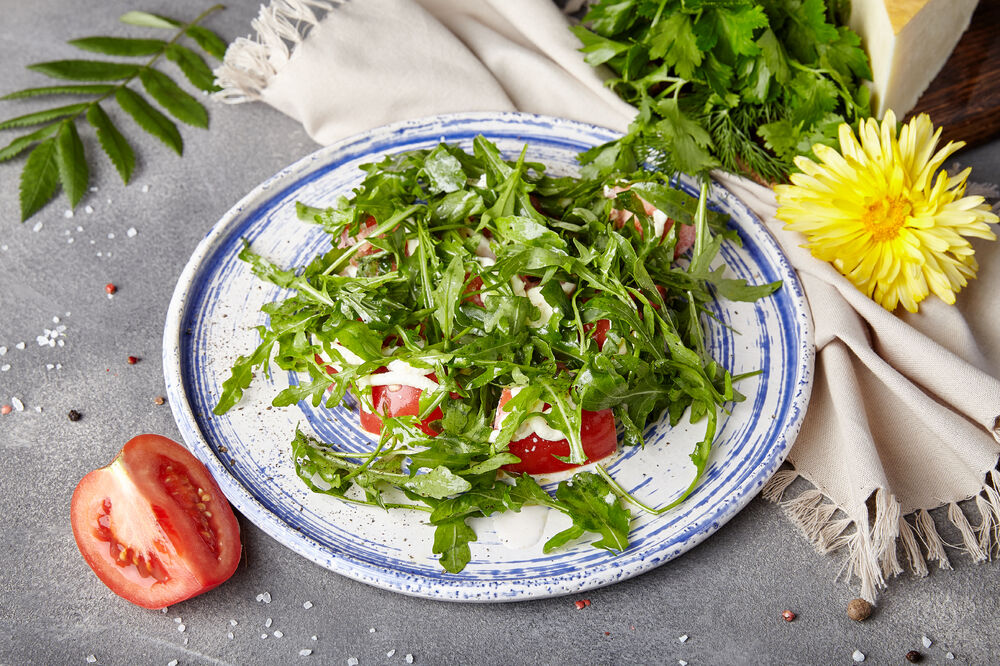 Salad of arugula with tomatoes and cream of smoked Suluguni