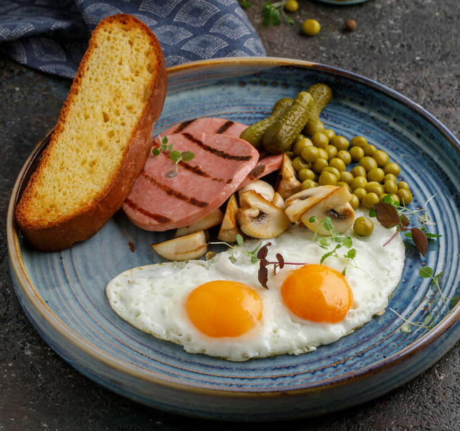 Fried eggs with grilled sausage and green peas