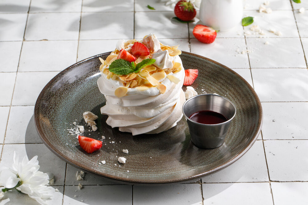 Dessert Meringue with butter cream and berry sauce