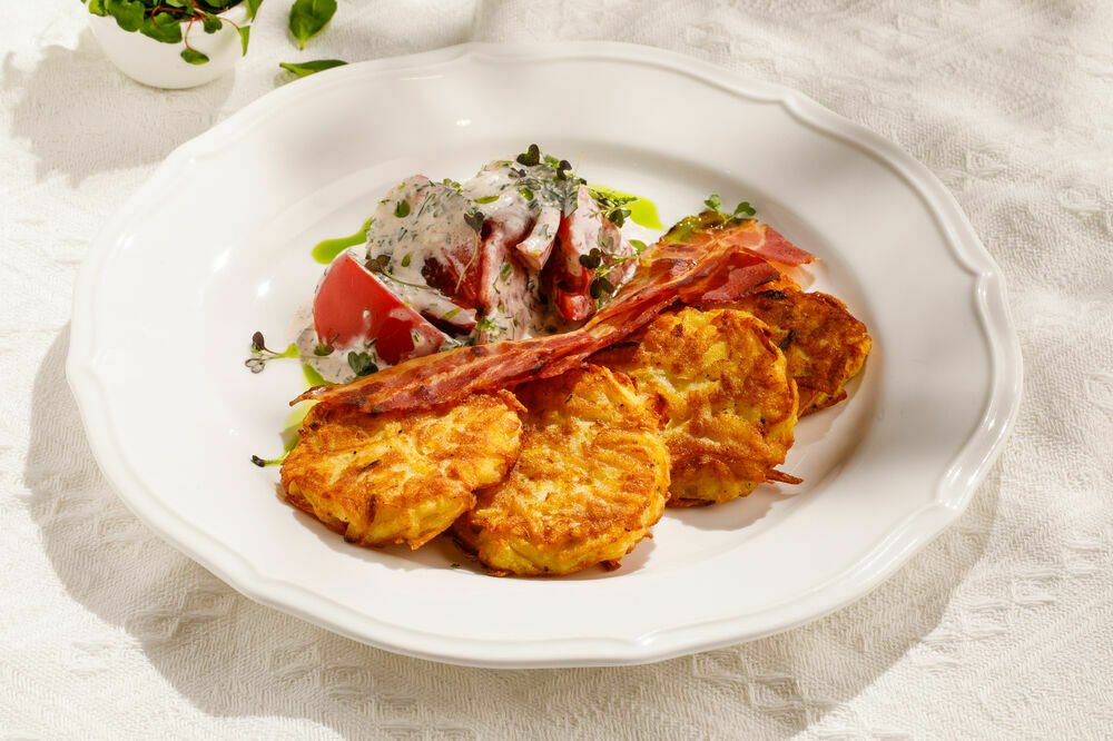 Potato pancakes with bacon, tomatoes and spiced sauce