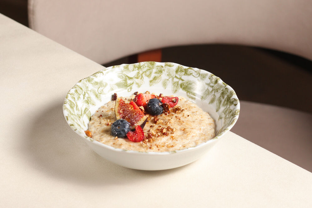 Oatmeal porridge on melted milk with berries and nuts
