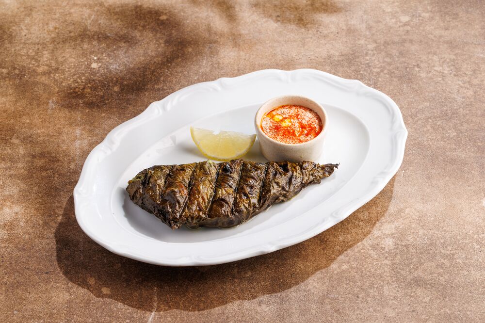 Fish in grape leaves over charcoal