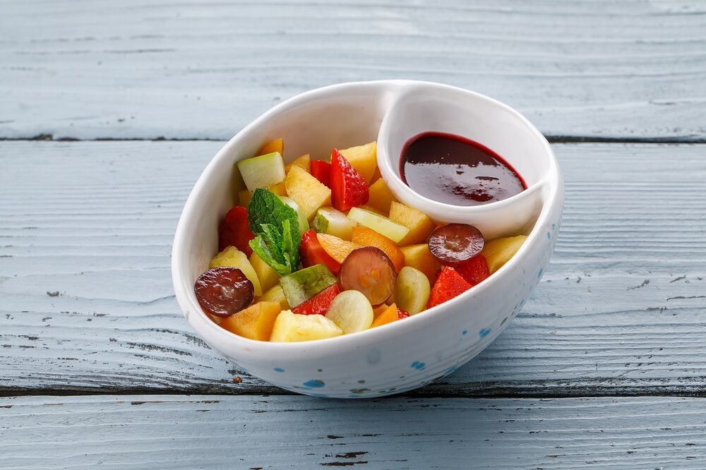 Fruit salad for children with berry sauce